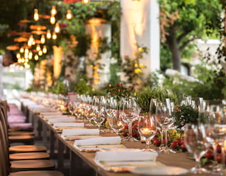 Rows of shimmering wine glasses on a long candlelit banquet table under a gazebo