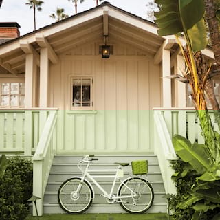 Electric bike with wicker basket leaning against white bungalow steps