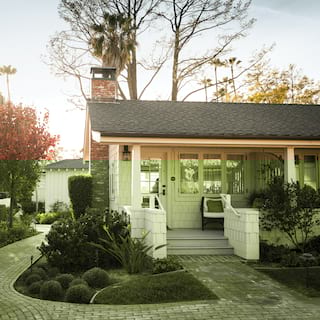 Bungalow among lush gardens with a red-brick path leading from steps