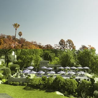 Side-view of a hillside infinity pool surrounded by blue parasols