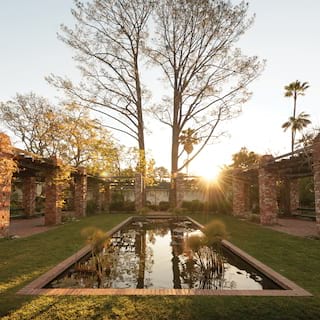 Rectangular lily pond surrounded by red-brick pergolas at sunset