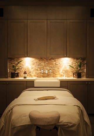 A spa treatment room in low light with spa table in the centre>