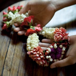 Close-up of two hands holding a sash made of real flowers