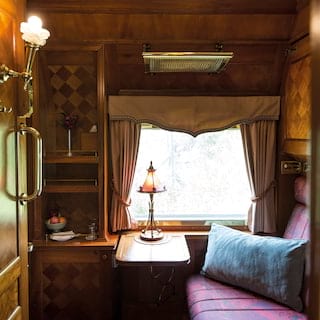 Train carriage with a blush coloured lampshade and ornate checkerboard marquetry