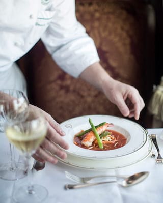 Close-up of a white gold-tipped bowl containing a red lobster soup
