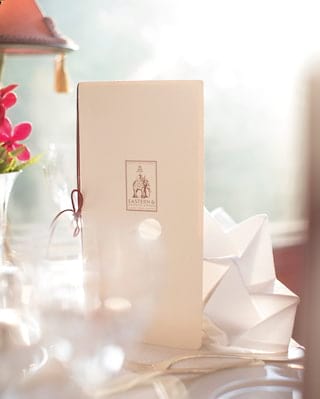 Close-up of a menu with an elephant illustration in red ink next to linen napkins