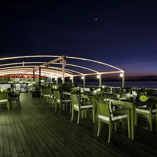 Wooden restaurant tables and chairs on a ship's top deck under the night sky