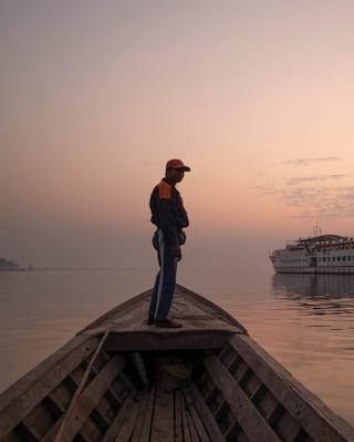 Un homme se tenant debout sur un bateau en bois sur la rivière Ayeyarwady