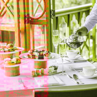 Close-up of a waitress pouring tea for a table laden with afternoon tea dishes
